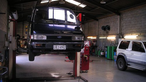 Tipps fürs Anschauen eines Gebrauchtwagens In einer Werkstatt wird ein Fahrzeug auf einer Hebebühne aufgebockt, um es durchzuchecken und zu reparieren